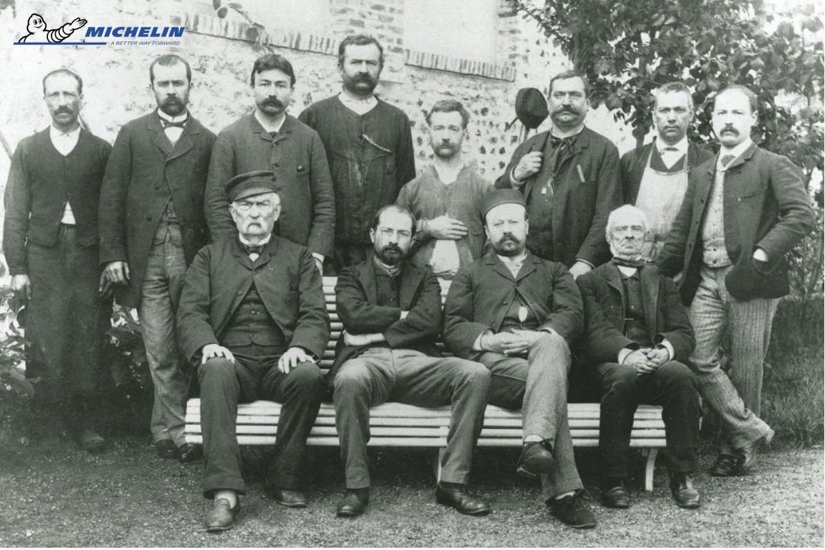 História firmy Michelin. Édouard Michelin (sedí druhý zľava) s personálom továrne v roku 1890.